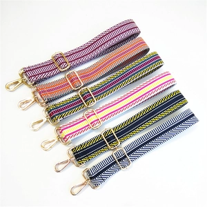 Close-up of adjustable striped handbag straps with gold metal lobster clasps and buckles
