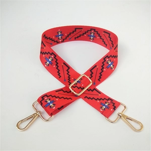 Close-up of ethnic red bag strap featuring geometric patterns and gold metal swivel hooks