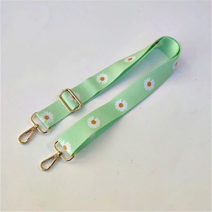Adjustable light green shoulder strap with white daisy pattern and gold metal hooks
