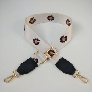Close-up of adjustable daisy pattern strap with gold metal hooks and black leather ends