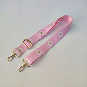 Pink fabric bag strap with white daisy pattern and gold metal hooks and buckle