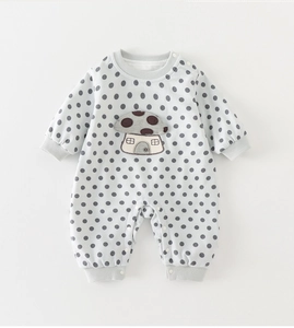 Close-up of baby romper with gray polka dots, mushroom patch and snap buttons