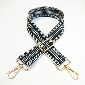 Detailed view of striped woven shoulder strap with polished gold lobster clasps and buckle