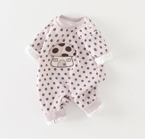 Close-up of pink polka dot baby bodysuit featuring cute mushroom embroidery and snap buttons