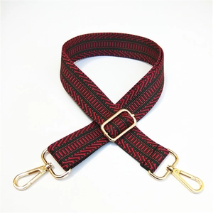 Close-up of thick striped nylon bag strap with red geometric pattern and gold buckles