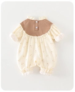 Detail of floral baby romper featuring scalloped collar and elasticated ruffled cuffs