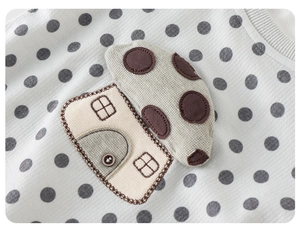 Detailed view of gray polka dot baby bodysuit with high-quality house applique and soft fabric