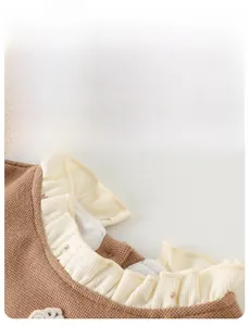 Detailed close-up of brown floral knitted baby romper with ruffled collar design