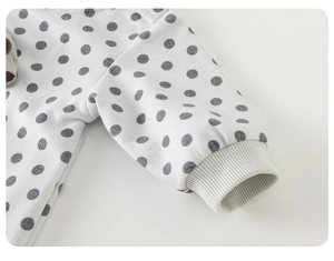 Close-up of ribbed cuffs and bear patch on polka dot long-sleeve cotton baby romper