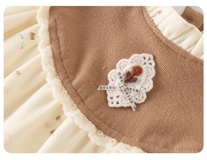 Detail of baby floral romper featuring lace trim, embroidered flower patch and brown knit
