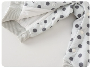 Close-up of baby romper showing soft grey polka dot fabric and durable white snap buttons