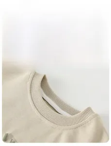Close-up detail of ribbed neckline and soft knit texture on beige baby sweatshirt