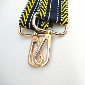 Macro detail of wide striped bag strap with premium gold metal lobster clasp