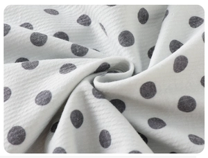 Detail of white knit fabric with gray polka dots and ribbed texture for baby romper