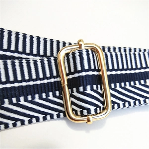 Close-up of blue and white striped woven bag strap with adjustable gold metal buckle