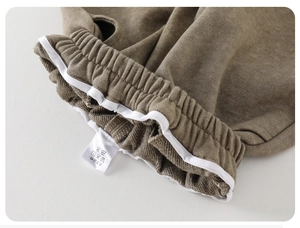 Detailed macro view of olive green knitted pants with elastic waistband and wash label