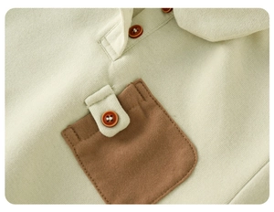 Détail macro du polo en tricot vert pour enfant avec poche marron et texture de bouton