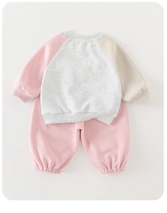 Detail of baby girl autumn set showing raglan sleeve stitching and ribbed knit cuffs