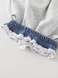 Gros plan d'un pantalon de jogging pour bébé gris avec taille élastique bleue et étiquette