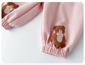 Detail of pink cotton baby pants featuring brown bear prints and elastic ribbed cuffs
