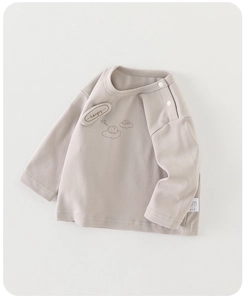 Détail d'un t-shirt bébé en coton à manches longues avec boutons-pression et broderie