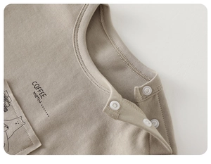 Close-up of cotton baby shirt with round neck, side shoulder buttons, and coffee print