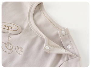 Détail de l'encolure en coton pour bébé avec boutons-pression blancs et broderie hérisson