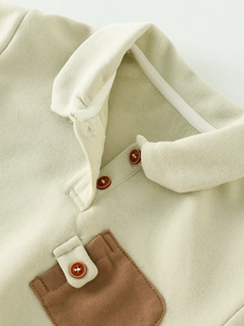 Détail du sweat-shirt en maille vert clair avec poche contrastée et col polo boutonné