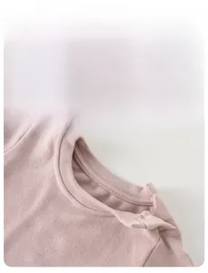 Close-up of pink knit baby shirt neckline showing soft fabric and metal snap buttons