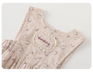 Detail of floral infant outfit featuring sunshine embroidery and white lace trim edge