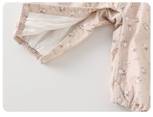Detailed close-up of snap fasteners on floral cotton baby romper in soft pink color