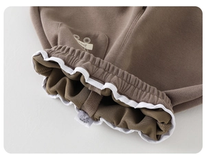 Detail of child's warm brown cotton joggers showing elastic waist with white wavy trim
