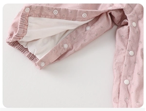 Macro view of pink floral baby romper featuring white snap buttons and ribbed cuffs