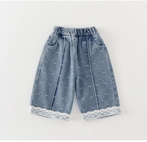 Detail of girls denim wide leg shorts with bow prints and delicate white lace hem