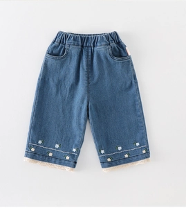 Dettaglio dei pantaloni in denim per bambine con ricami floreali e bordo in pizzo