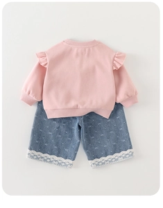 Close-up of pink long-sleeved sweatshirt with ruffles and bow pattern denim shorts
