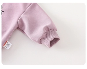 Detailed macro view of soft ribbed sleeve cuffs and wash label on a purple baby sweatshirt
