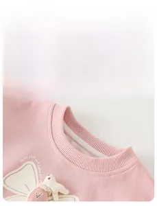 Close-up of pink crew neck with 3D bunny doll and flower embroidery on cotton fabric