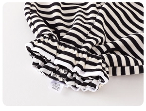 Detail of baby striped trousers showing elastic ribbed cuffs and stitched wash care label