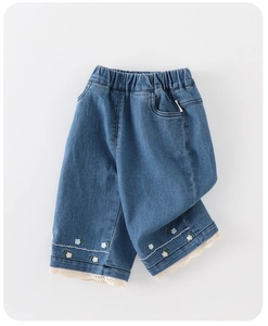 Dettaglio di jeans da bambina con ricamo floreale e bordo in pizzo bianco sul fondo