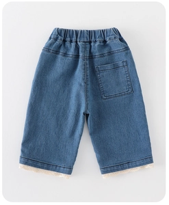 Dettaglio dei jeans blu da bambina con bordo in pizzo bianco sui polsini e vita elasticizzata