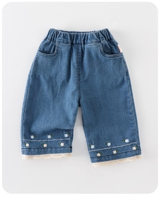 Dettaglio di jeans da bambina con ricamo floreale, bordo in pizzo e vita elastica