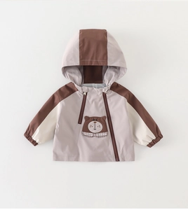 Detail of baby hooded jacket featuring cartoon bear embroidery and color-block design