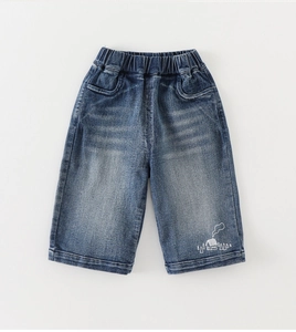 Detail of boys denim jeans with elastic waistband and white house pattern embroidery