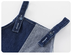 Détail de la salopette en jean pour bébé avec patchwork bleu et fermeture à bouton rond