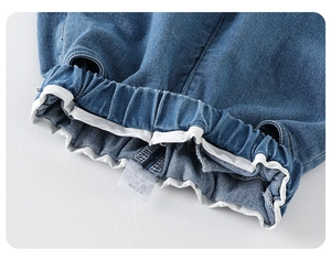 Dettaglio dell'elastico in vita dei jeans blu con bordino bianco ed etichetta interna