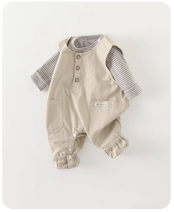 Close-up of baby beige cotton overalls with wood buttons and striped long sleeve shirt