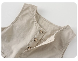 Detail of baby overalls featuring classic dark buttons on premium beige cotton fabric