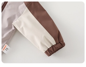 Close-up of baby jacket elastic cuff with brand label on beige and brown fabric