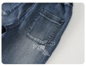 Detail view of dark blue boys jeans with artistic white house and forest pattern print